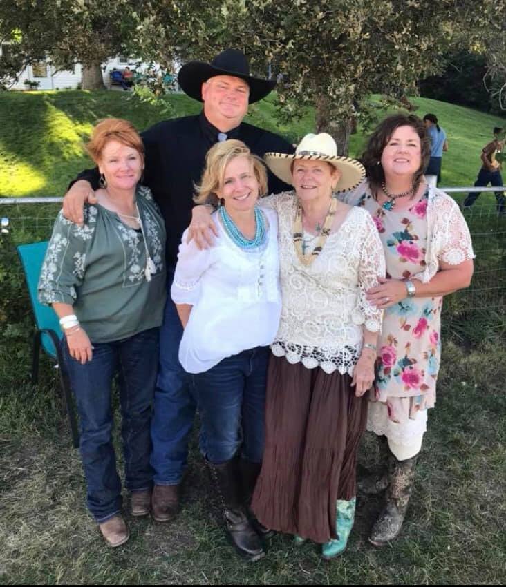 An elderly woman with her grown children:  one very tall man in a cowboy hat and three beautiful ladies.